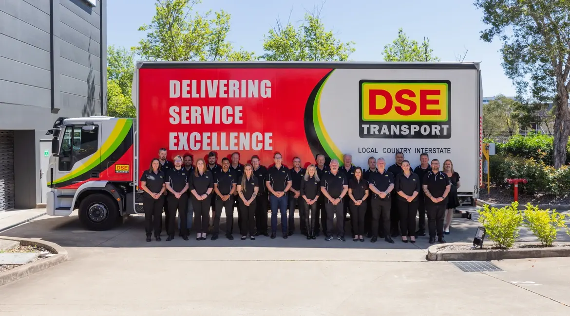 The DSE Transport team lined up in front of a branded pantech truck reading Delivering Service Excellence