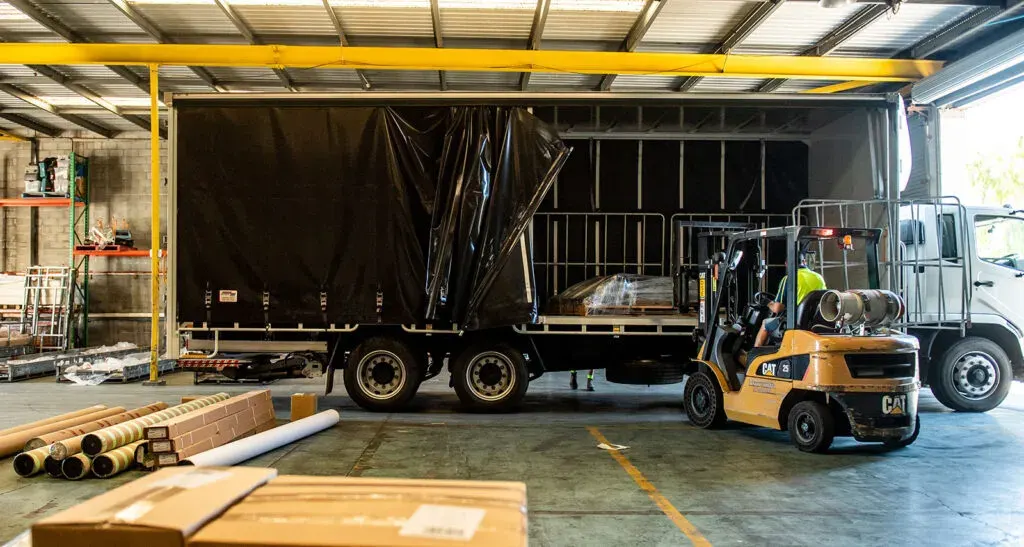 Forklift loading palletised freight onto a DSE Transport tautliner inside the depot warehouse