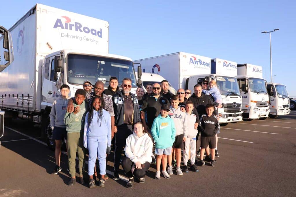 AirRoad team members and families standing in front of branded trucks at the Sydney charity convoy fundraiser.