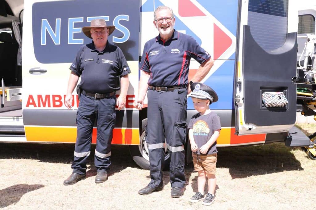 NETS medical transport staff with a former young patient beside a NETS ambulance at the Sydney charity convoy.