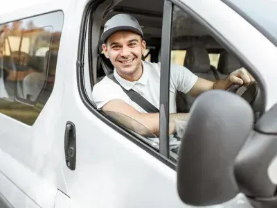 Smiling delivery driver at the wheel of a white home delivery van