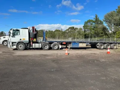 DSE Transport flattop semi-trailer fitted with a vehicle-mounted crane, parked in the depot yard