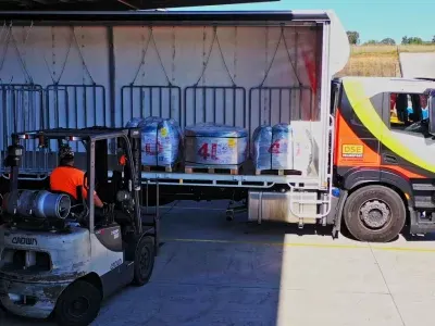Forklift operator unloading palletised factory freight from an open DSE Transport curtain-sider