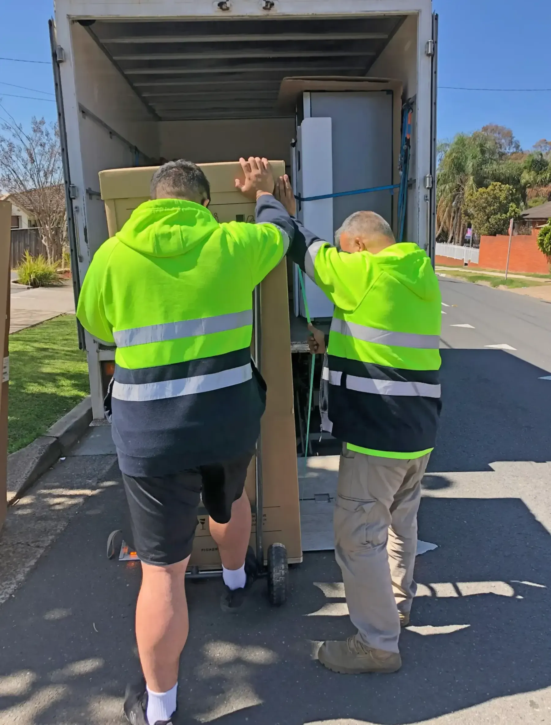 DSE Transport crew carefully unloading a large appliance from the truck during a home delivery